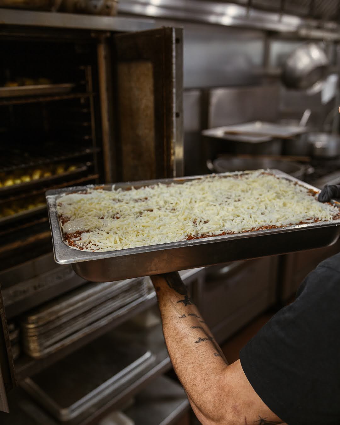 Large authentic Italian lasagna in tray being put into oven for catering order at Trattoria Pasquale in Tampa, Florda